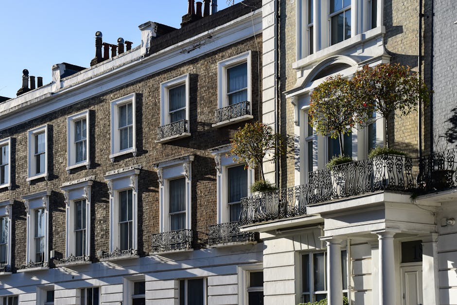 Exterior view of a multi-storey Victorian-style townhouse during a home relocation, featuring a light-colored facade with detailed architectural features such as decorative window trims, balustrades,