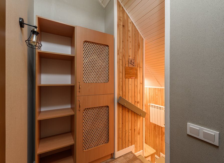A wooden staircase with a handrail leading down to a narrow hallway in an Islington, London home, with wooden paneling on the walls and a radiator visible on the lower wall. To the left of the stairca